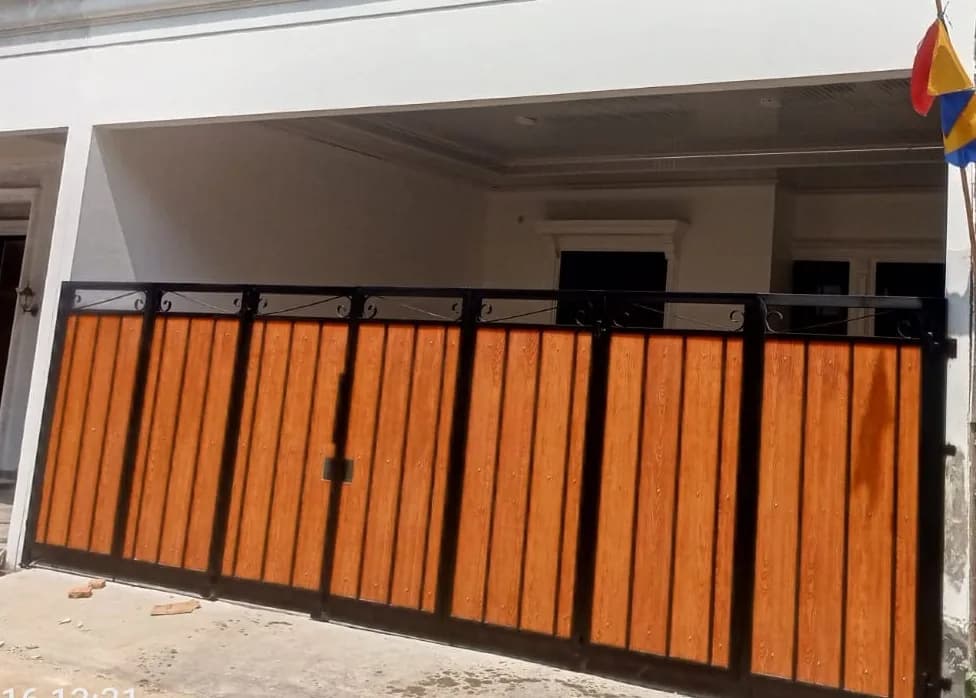 Pagar besi panel motif kayu dengan bingkai hitam di teras rumah