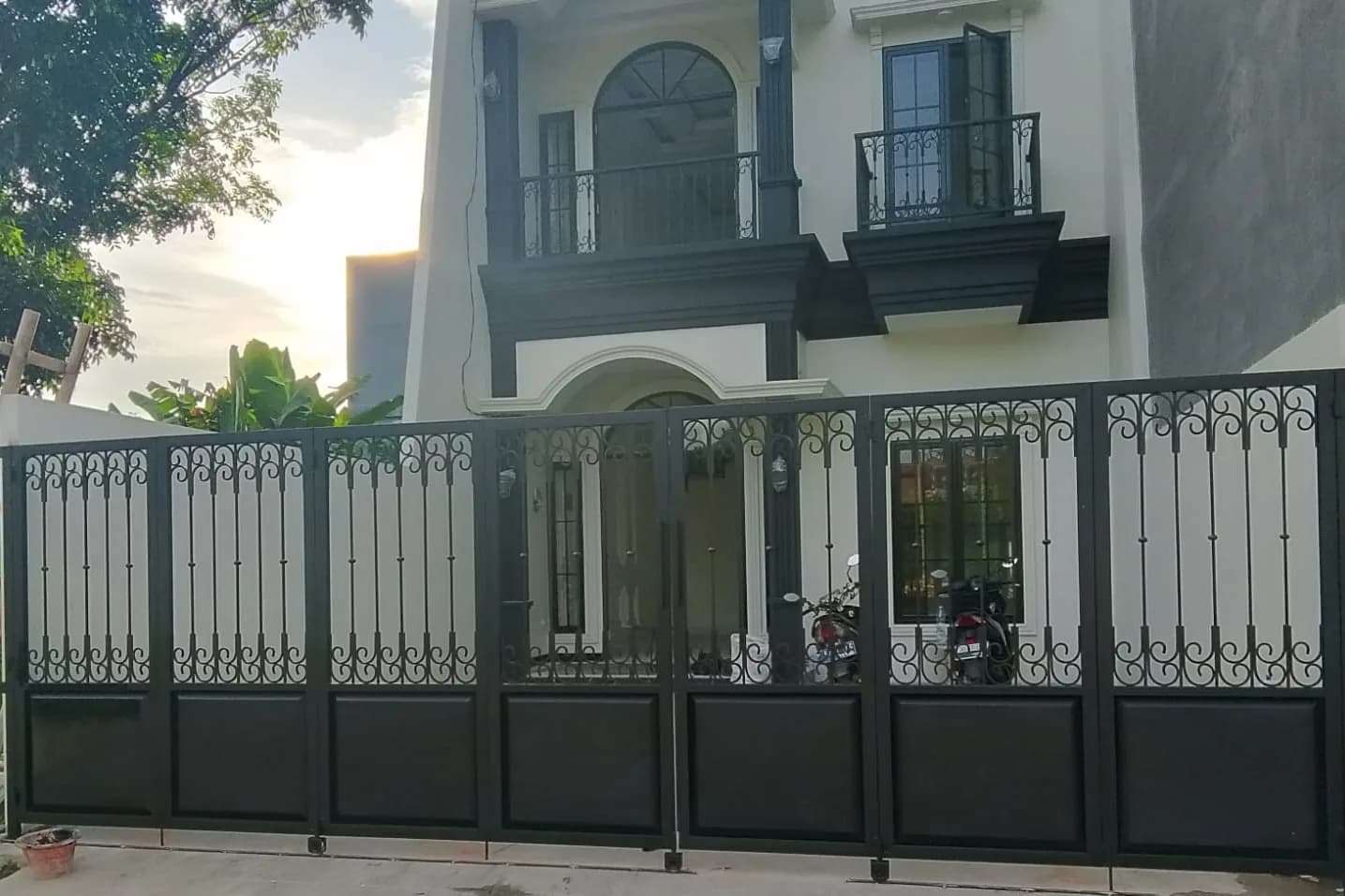 Pagar besi swing gate mewah motif scroll pada rumah dua lantai bergaya klasik
