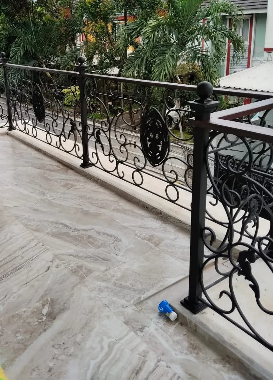 Railing balkon besi tempa motif scroll dengan medali bundar