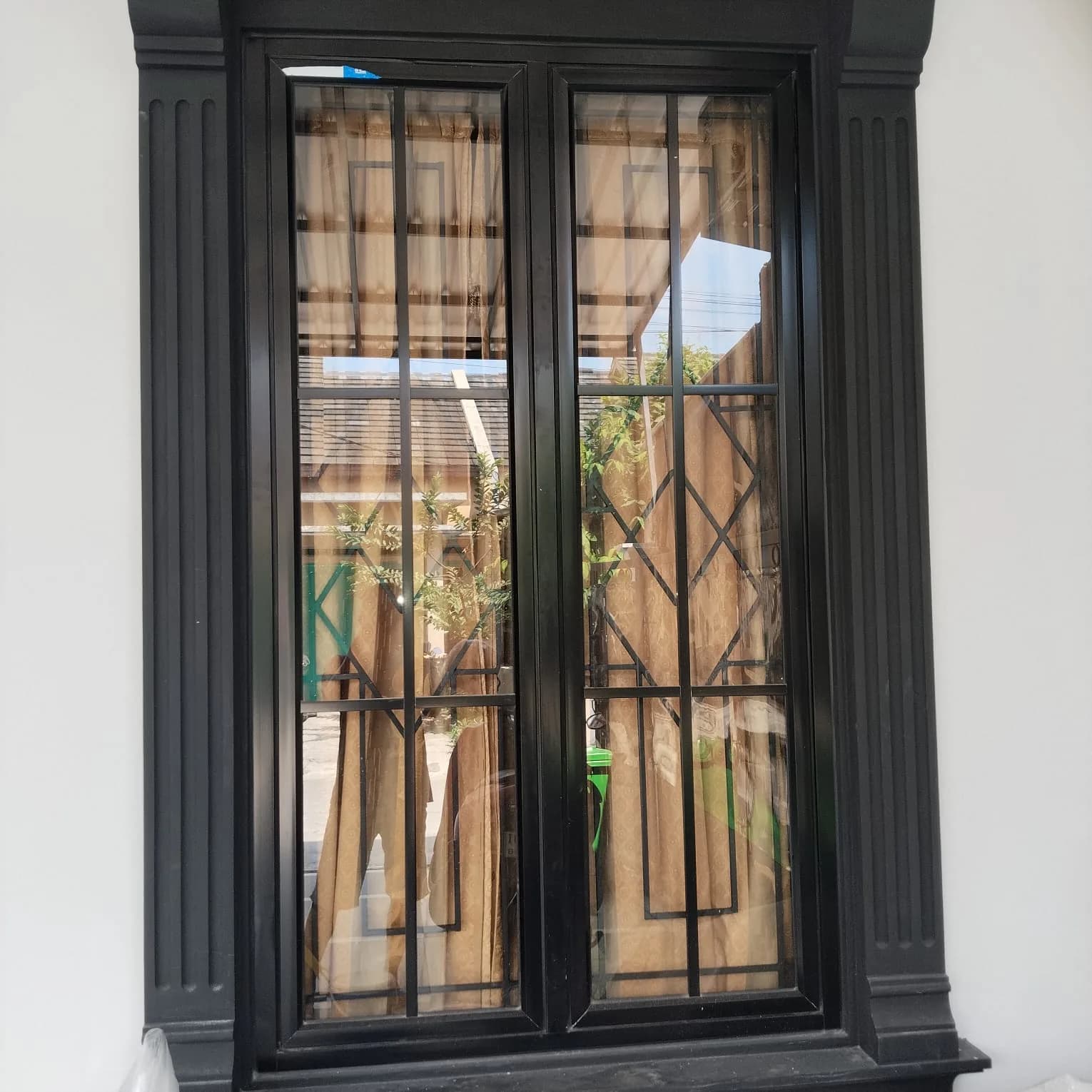 Teralis jendela besi hitam minimalis dengan bingkai tebal pada rumah bergaya modern