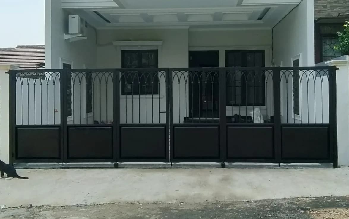 Pagar besi swing gate dengan motif lengkung klasik pada rumah dua lantai