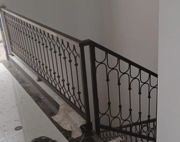 Railing balkon besi dengan pola lengkung berulang