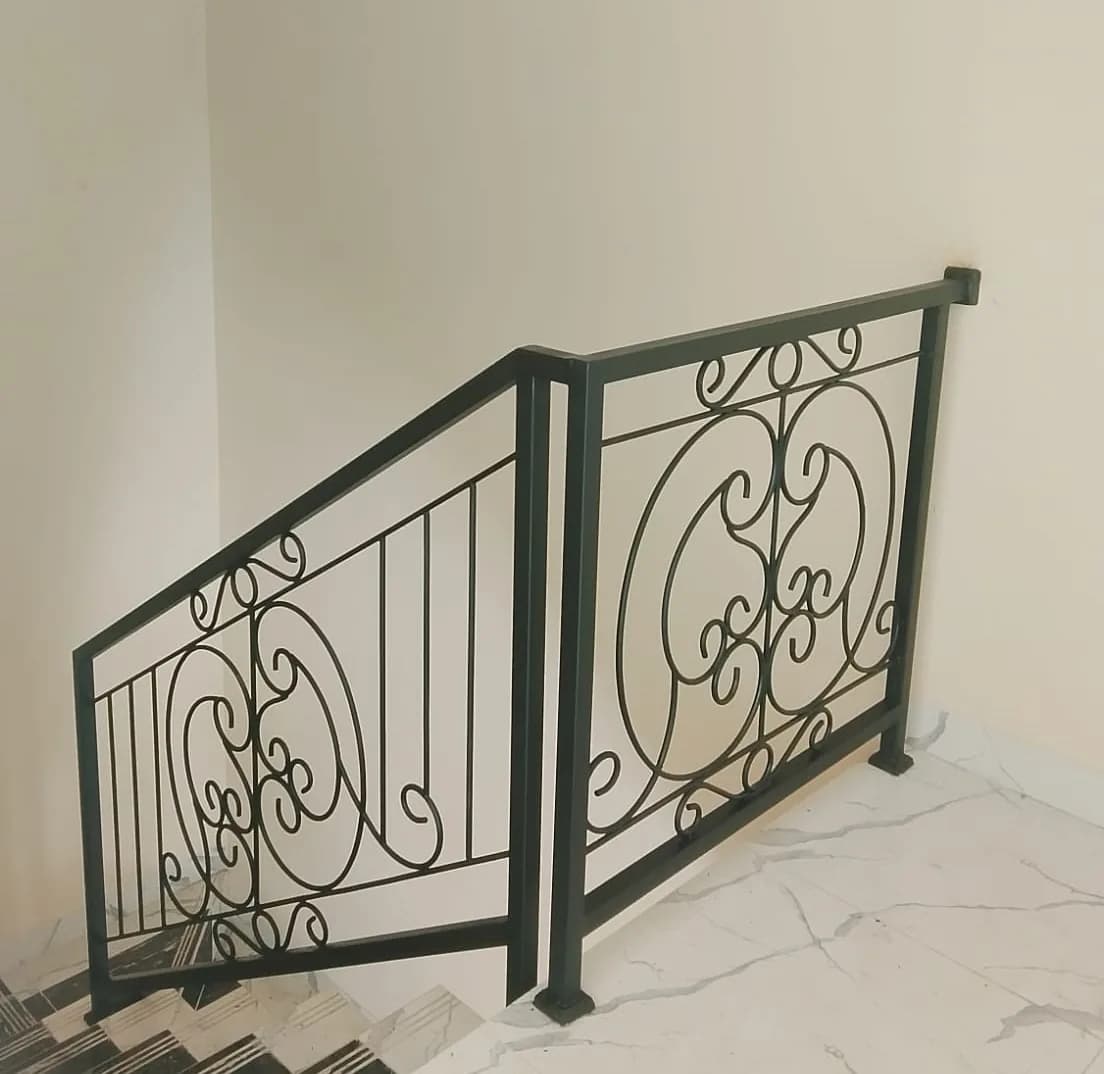 Railing tangga besi dengan motif medali lingkaran pada sisi dinding